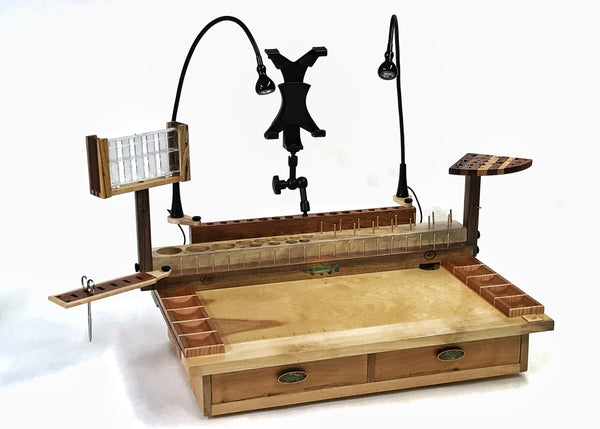 The two drawer Rainbow fly tying bench with a trash drop hole in the right rear corner. The dubbing dispenser swivel is an accessory that can be added to the bench on the opposite end of the tool swivel plate.  These can be mounted on either side of the bench using two thumb screws. The photo also shows the other accessories that can be added to the bench.
